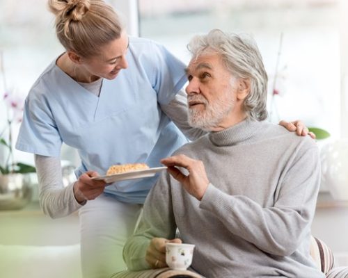 An older man receiving food from a nurse