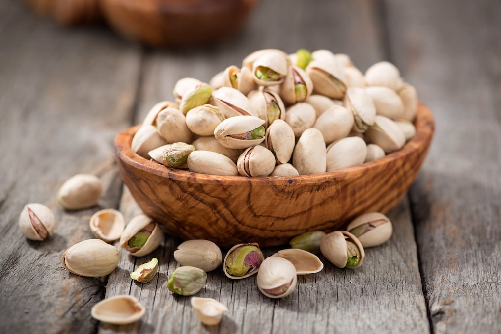 Bowl with pistachios on a wooden table.