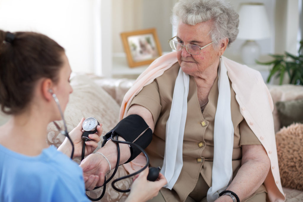 person gets blood pressure checked by at-home nurse