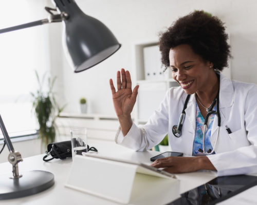 female doctor waves to patient via video call