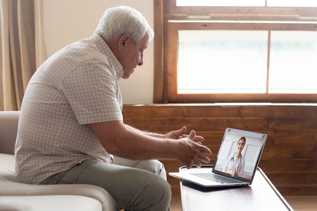 elderly man learning how to schedule a telehealth appointment with his doctor