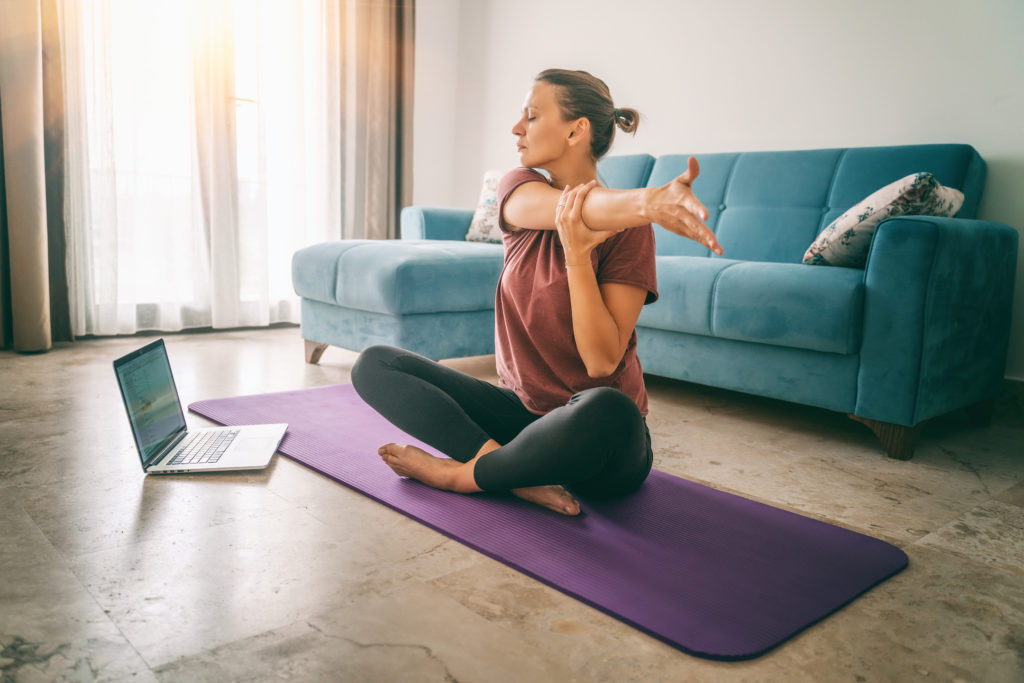 Young woman doing yoga at home to manage stress and maintain heart health
